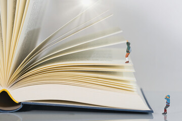 climbers, mountaineers climb a book in sunshine, light background