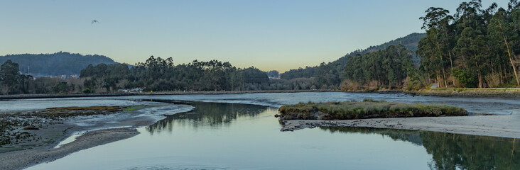panorama of marshes with forests and mountains in the background at sunset