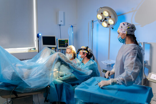 Professional team of surgeons proctologist performing operation using special medical devices in the operating room in hospital. Urgent surgical concept