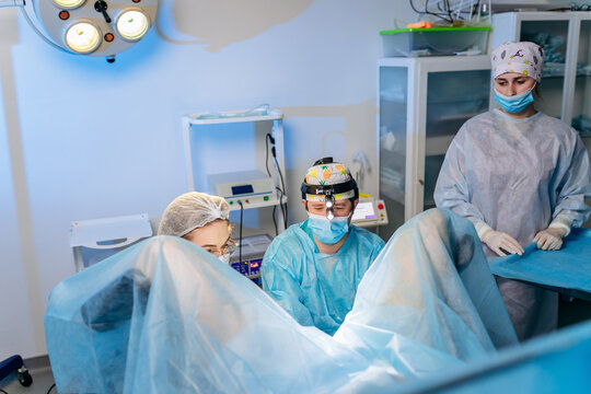 Professional team of surgeons proctologist performing operation using special medical devices in the operating room in hospital. Urgent surgical concept