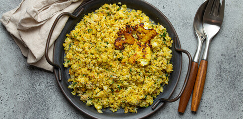 Fried cauliflower rice or couscous with dill on plate, healthy low carbohydrates vegetable side dish for keto diet and healthy low calories nutrition on rustic stone background