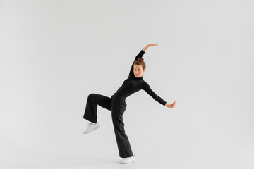 Young Girl, professional hip-hop dancer in a black clothes performing over a Isolated white background with a plenty of copy space.