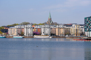 Stockholm. Spring. A buildings with a red and black roofs is in the background. Boat on the water.