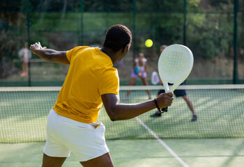African american tennis player with a padel racket training on an outdoor court with a partner