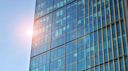 Fototapeta na wymiar Looking up at the commercial buildings in downtown. Modern office building against blue sky. Windows of a modern glass building.
