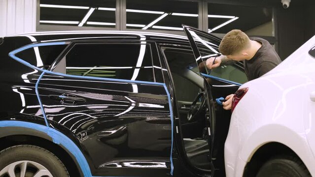 Man covering car with vinyl polyurethane tape. Films for the car. Sticker protective film on the car