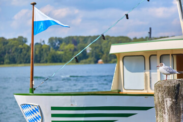 Obraz premium Schöner Blick von der Anlegestelle, in Prien am Chiemsee auf ein Ausflugsschiff, mit einer Möwe im Vordergrund. In Bayern, Deutschland.