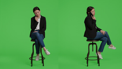 Caucasian businesswoman answering call on smartphone, sitting on chair in studio background. Office...