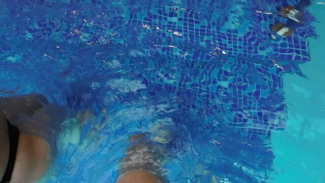 Man and woman enter or exit swimming pool by steps. POV male barefoot legs.