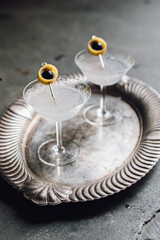 two gin Aviation cocktails with lemon, cherry garnish on silver tray