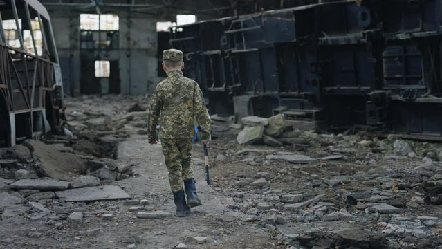 Back View of the Little Soldier Going Through the Ruins Holding the Toy Gun. War. Male Warrior. Military Operation, Assault, Battle with the Enemy