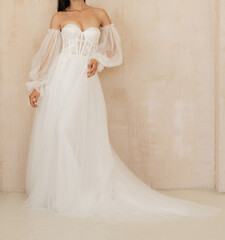 Pretty bride dressed in white long wedding dress with a deep neckline, laced corset and with fancy...