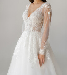 Bride dressed in a white wedding dress with a deep neckline, laced corset and fancy long sleeves....
