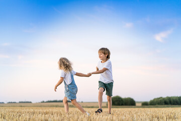 Fototapeta premium Happy and free people, children run through the beveled field of wheat
