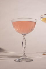 sparkling pink rose wine in crystal coupe glass against white background