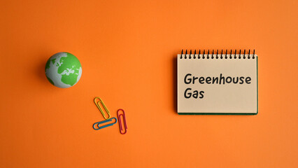 There is a notebook with the word Greenhouse Gas. It is eye-catching image.