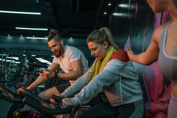 A young, handsome man works out during a spinning session on a cycling machine at the gym with his friends.	
