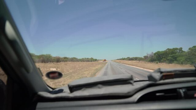 POV car driving on asphalt highway. Left side traffic. Savannah road in Africa.