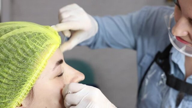 beautician removes hairs on a woman's face with a thread. eyebrow correctio