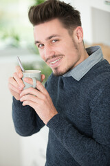 Fototapeta cheery youthful guy resting with mug of hot beverage indoor obraz