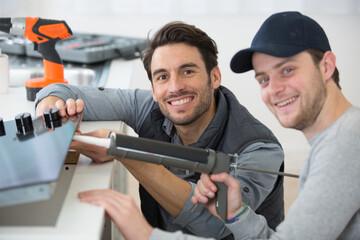 portrait of two men installing kitchen hob