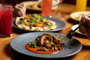 Delicious grilled octopus dish with red sauce, served at the table of a luxurious restaurant.