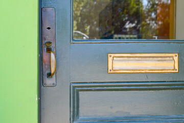 A dark green wooden door with half glass pane window, and a wooden panel. The vintage door has a...