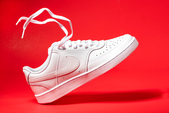 Nike white sneakers product shot isolated on red background. Illustrative editorial photo.
