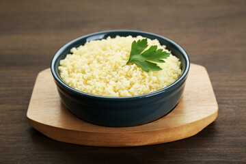 Tasty couscous with parsley on wooden table, closeup