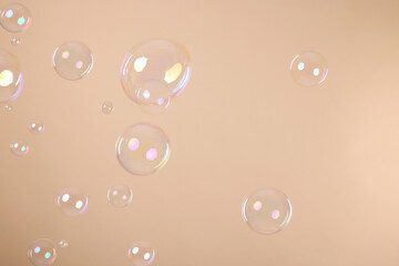 Many beautiful soap bubbles on beige background
