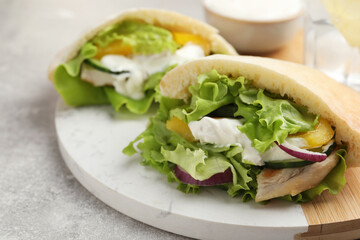 Delicious pita sandwiches with chicken breast and vegetables on light gray table, closeup