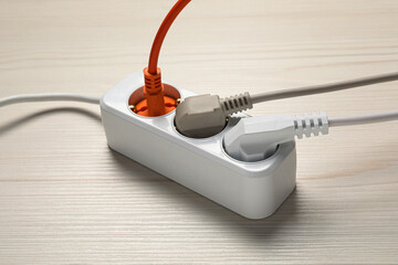 Extension cord with electrical plugs on white wooden floor. Electrician's equipment