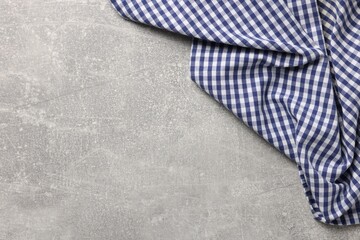 Blue checkered tablecloth on light gray textured table, top view. Space for text