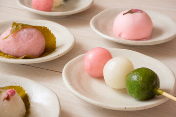 Japanese sweets in spring. Three-color dumplings, sakura mochi, buns. 春の和菓子。3色団子、桜餅、饅頭