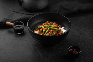 Asian cooked beef with spring onion and rice on black background