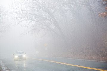 Thick fog with a car driving carefully along a curvy road near Minneapolis Minnesota