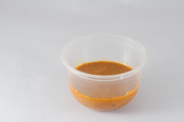 peanut sauce served in a transparent plastic bowl isolated on white background