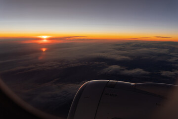 Fototapeta na wymiar Bright orange sunrise on the horizon over grey clouds