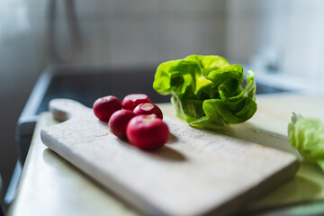 A top side and close up view of middle aged woman making a salad on a cutting board