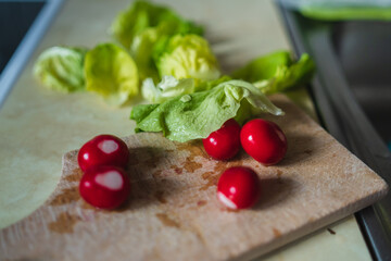 A top side and close up view of middle aged woman making a salad on a cutting board
