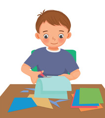 Cute little boy cutting colored paper with scissors making paper cut art craft