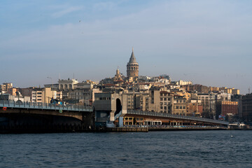 Obraz premium Beyoglu district with Galata Tower and Galata Bridge in the foreground from the waters of the Golden Horn Bay on a sunny day, Istanbul, Turkey