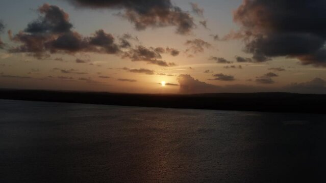 Trucking right aerial shot of a stunning golden sunset from the famous tourist destination alligator beach at a large river in Cabedelo, Paraiba, Brazil near the coastal capital city of Joao Pessoa.