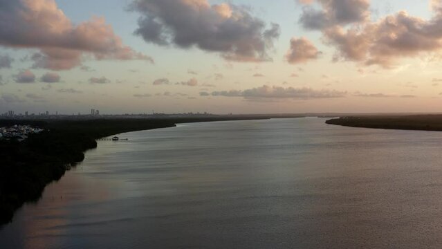 Descending aerial drone shot of the famous tourist destination alligator beach at a large river in Cabedelo, Paraiba, Brazil near the coastal capital city of Joao Pessoa during a vibrant summer sunset