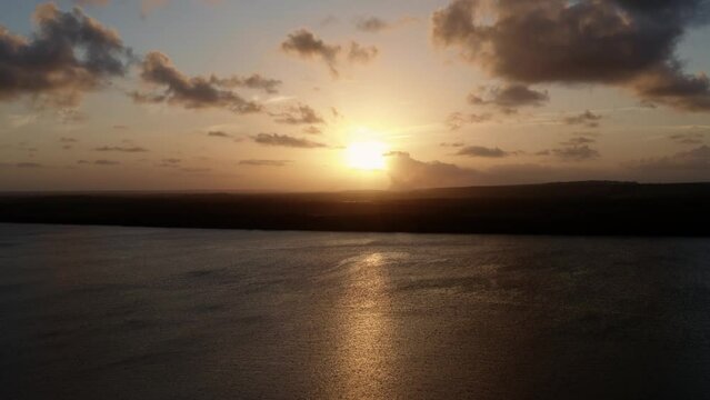 Rising aerial drone shot of a stunning golden sunset from the famous tourist destination alligator beach at a large river in Cabedelo, Paraiba, Brazil near the coastal capital city of Joao Pessoa.