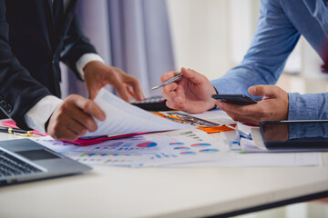 Businessmen analyzing investment graphs, brainstorming meeting and discussing plans in conference room. Using graph sheets, laptops and calculators. business and investment ideas
