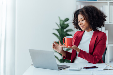 happy young businesswoman African American siting on the chiar cheerful demeanor raise holding coffee cup smiling looking laptop screen.Making opportunities female working successful in the office.
