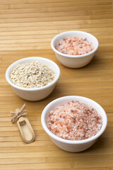 White bowls filled with coarse Himalayan salt and oats.