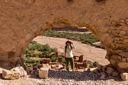 Woman in front of Ait Benhaddou through a stone archway in Morocco