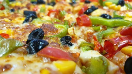 Delicious vegetable pizza with a lot of cheese, olives and other toppings